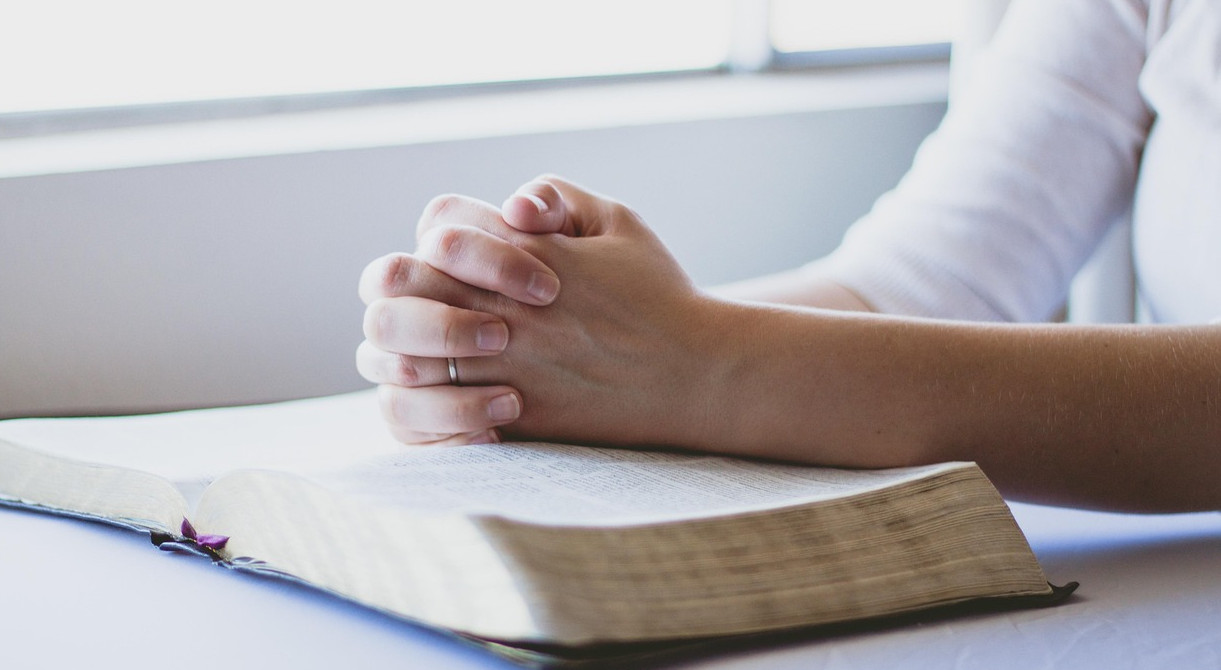 Praying hands on the Bible